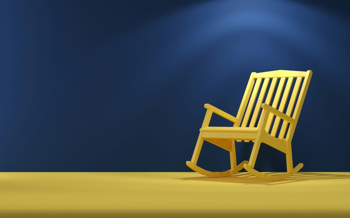 a wooden rocking chair sitting on top of a yellow floor by Mehdi Mirzaie courtesy of Unsplash.